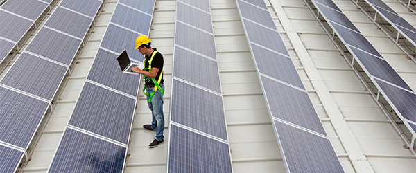 Man standing among solar panels in solar array